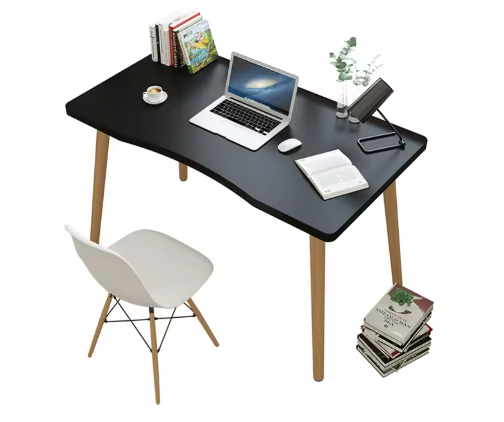 A simple design computer desk with a black rectangular MDF top and wooden legs, displayed in a home setting with a laptop, books, and a plant on it.