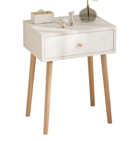 A white, modern pine wooden side table with a single drawer and wooden legs, with items placed on top.