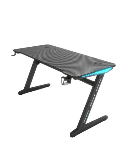 A black gaming desk with Z-shaped legs and a carbon fiber surface, equipped with an LED light on the edge.