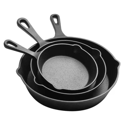 Set of three black cast iron skillets on a white background