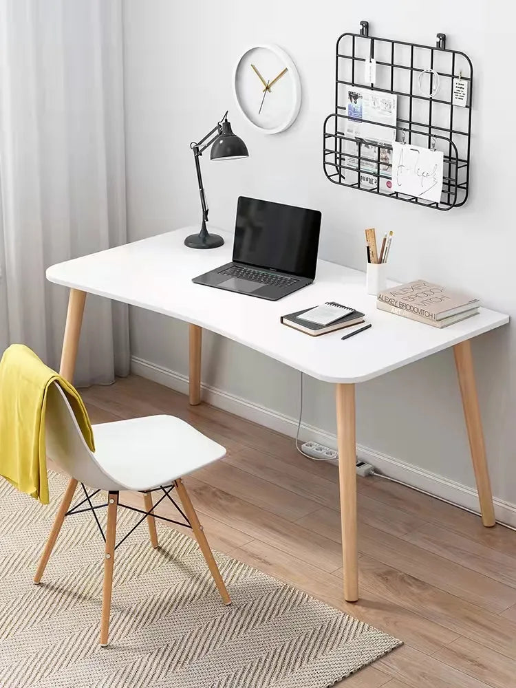 Minimalist home office desk with a laptop, lamp, and decor in a light-colored room.