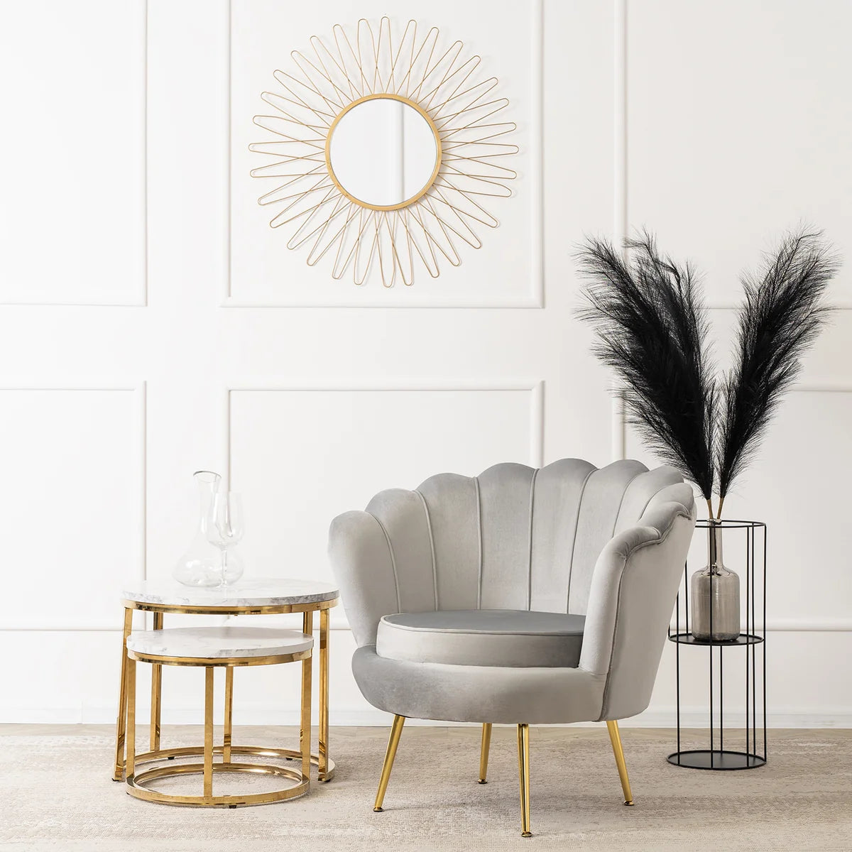 Gray shell-shaped chair with gold legs in a room with a decorative mirror and pampas grass.